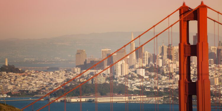 San Francisco cityscape with the Golden Gate Bridge tower in the foreground during sunset, USA