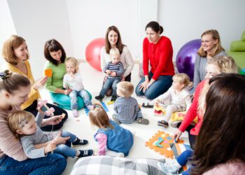 Children with mothers sit in a circle and study colors, numbers and figures in the kindergarten