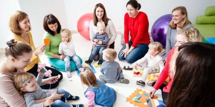 Children with mothers sit in a circle and study colors, numbers and figures in the kindergarten