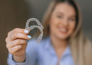A cheerful woman showing transparent teeth aligners, emphasizing dental care and orthodontic treatment solutions for enhancing smiles and bite alignment.