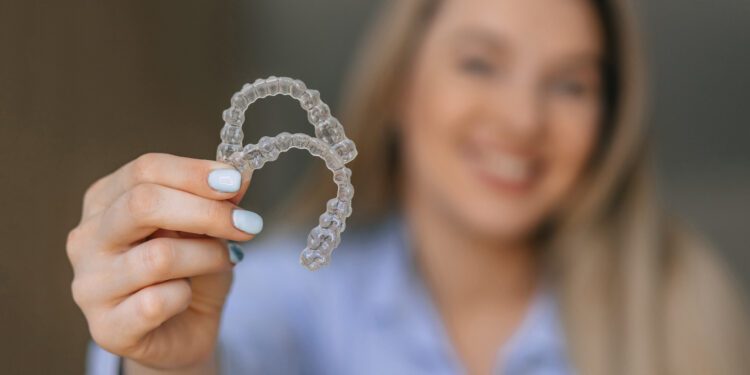 A cheerful woman showing transparent teeth aligners, emphasizing dental care and orthodontic treatment solutions for enhancing smiles and bite alignment.