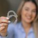 A cheerful woman showing transparent teeth aligners, emphasizing dental care and orthodontic treatment solutions for enhancing smiles and bite alignment.