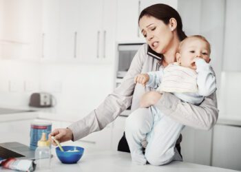 Its always a rush in the morning. an overwhelmed mother trying to multitask while holding her baby boy