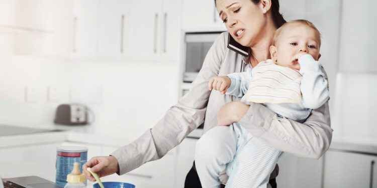 Its always a rush in the morning. an overwhelmed mother trying to multitask while holding her baby boy